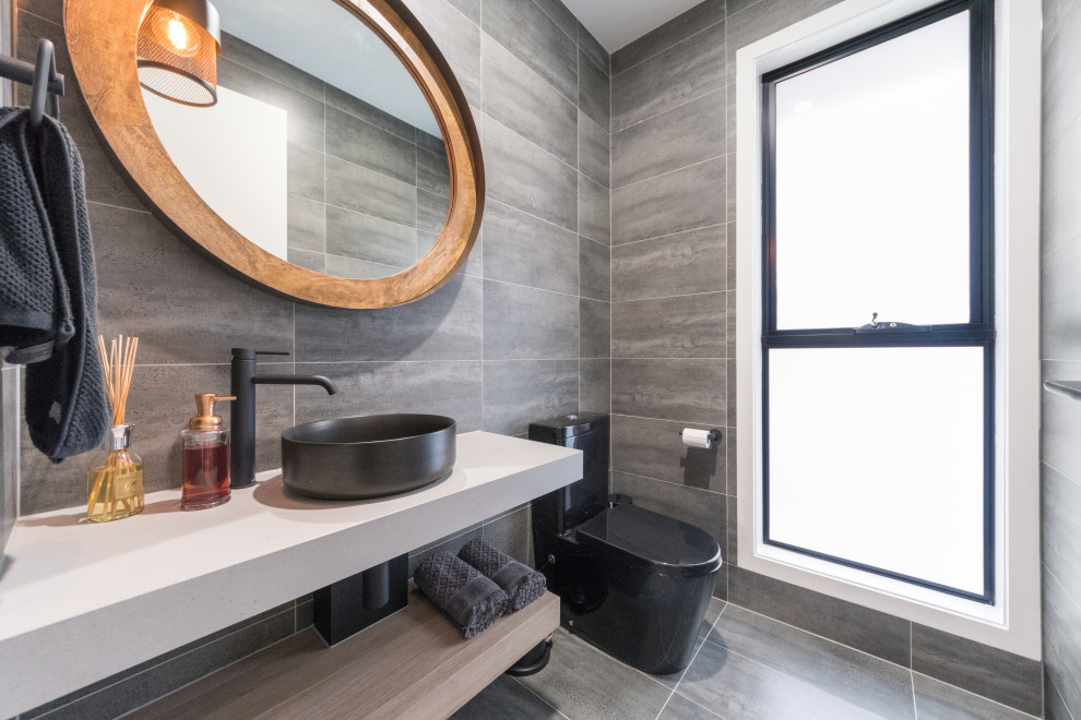 Photo of a mid-sized contemporary powder room in Gold Coast - Tweed with grey cabinets, a one-piece toilet, gray tile, a console sink and a floating vanity.