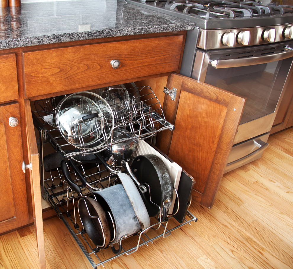 Inspiration for a transitional l-shaped light wood floor open concept kitchen remodel in Milwaukee with a farmhouse sink, shaker cabinets, medium tone wood cabinets, granite countertops, gray backsplash, glass tile backsplash, stainless steel appliances and an island