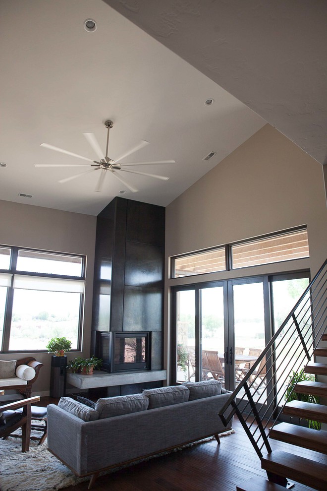 This is an example of a mid-sized contemporary formal open concept living room in Denver with grey walls, dark hardwood floors, a two-sided fireplace, a concrete fireplace surround, no tv and brown floor.