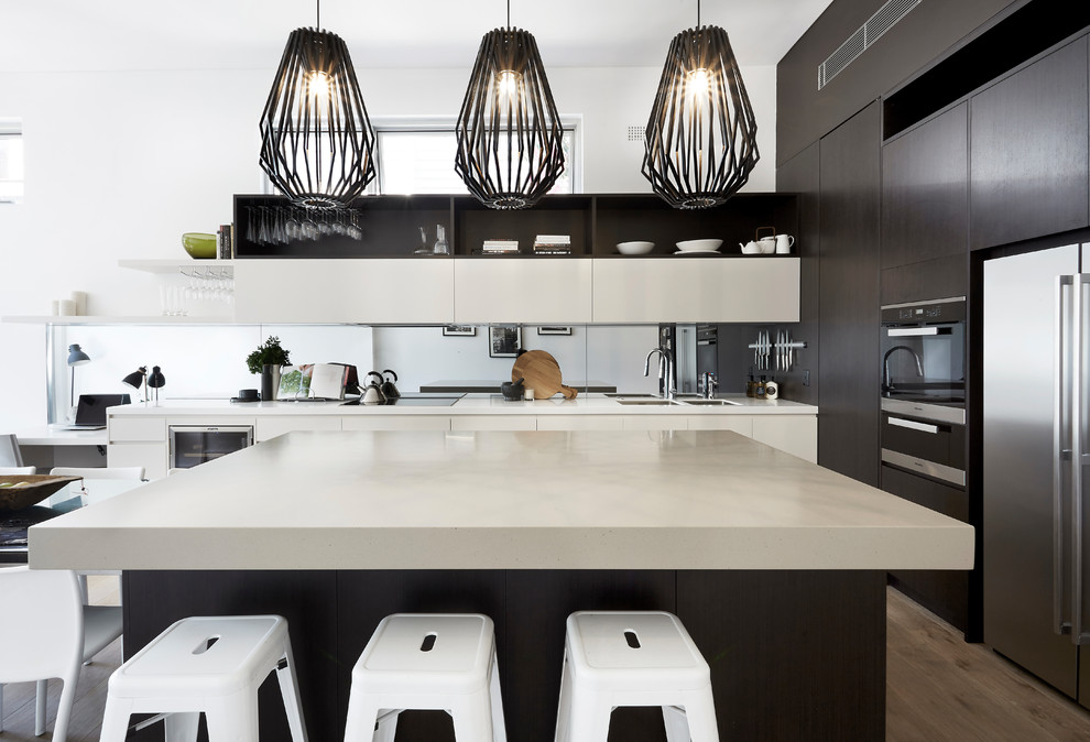 Mid-sized contemporary l-shaped open plan kitchen in Sydney with with island, a double-bowl sink, flat-panel cabinets, mirror splashback, stainless steel appliances and beige benchtop.