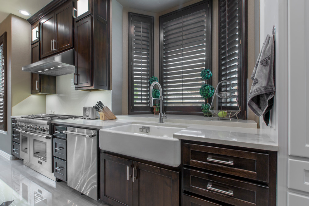 Inspiration for a large modern l-shaped ceramic tile and beige floor eat-in kitchen remodel with a farmhouse sink, shaker cabinets, dark wood cabinets, quartzite countertops, beige backsplash, stainless steel appliances, an island and beige countertops