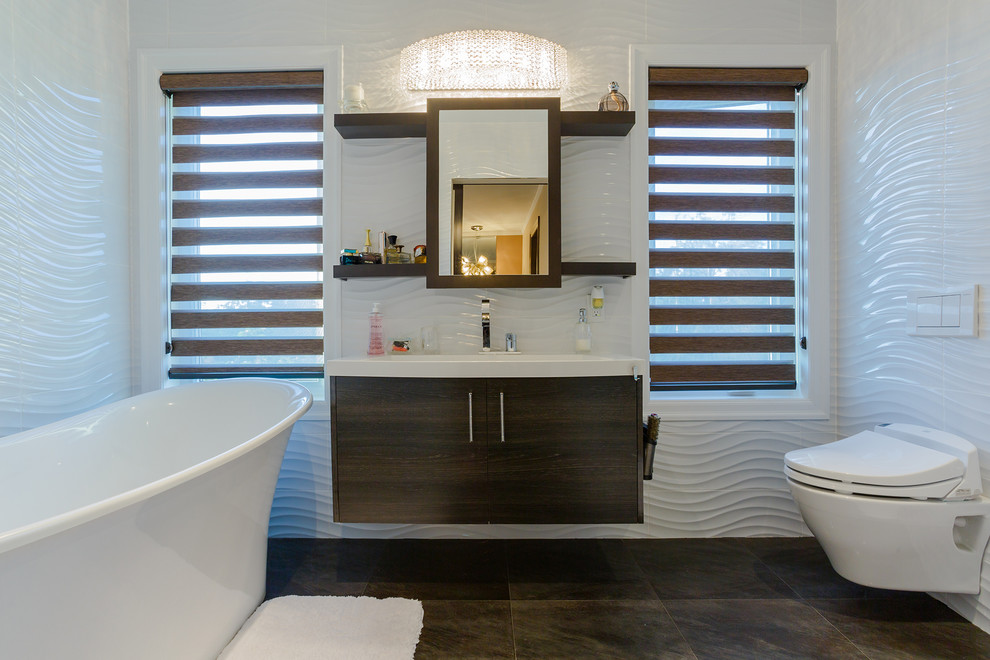 Inspiration for a large modern master bathroom in Toronto with flat-panel cabinets, dark wood cabinets, a freestanding tub, a wall-mount toilet, white walls, porcelain floors, a wall-mount sink and brown floor.