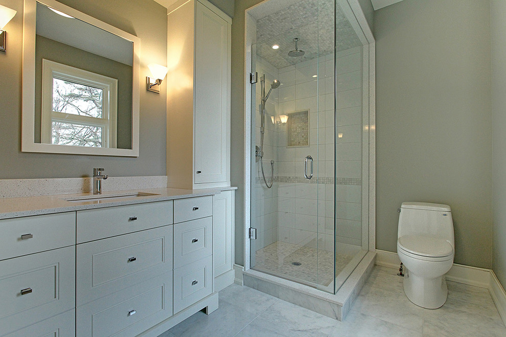 Photo of a mid-sized transitional 3/4 bathroom in Toronto with shaker cabinets, white cabinets, a freestanding tub, a corner shower, a one-piece toilet, grey walls, marble floors and an undermount sink.