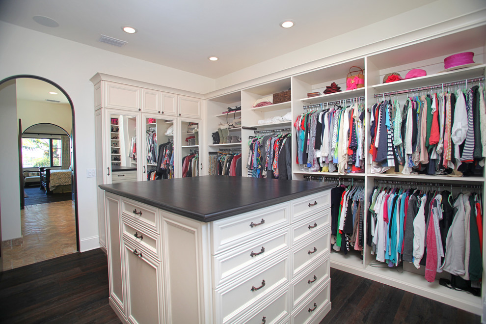Photo of a mid-sized traditional gender-neutral walk-in wardrobe in Tampa with recessed-panel cabinets, white cabinets, dark hardwood floors and brown floor.