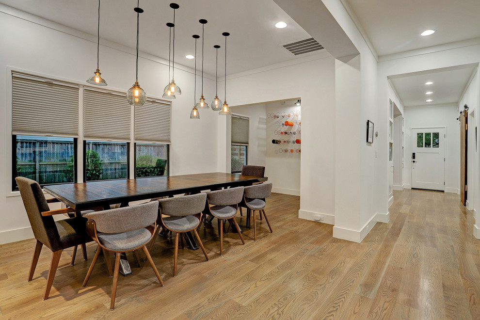 This is an example of a large modern kitchen/dining combo in Houston with white walls, medium hardwood floors and brown floor.