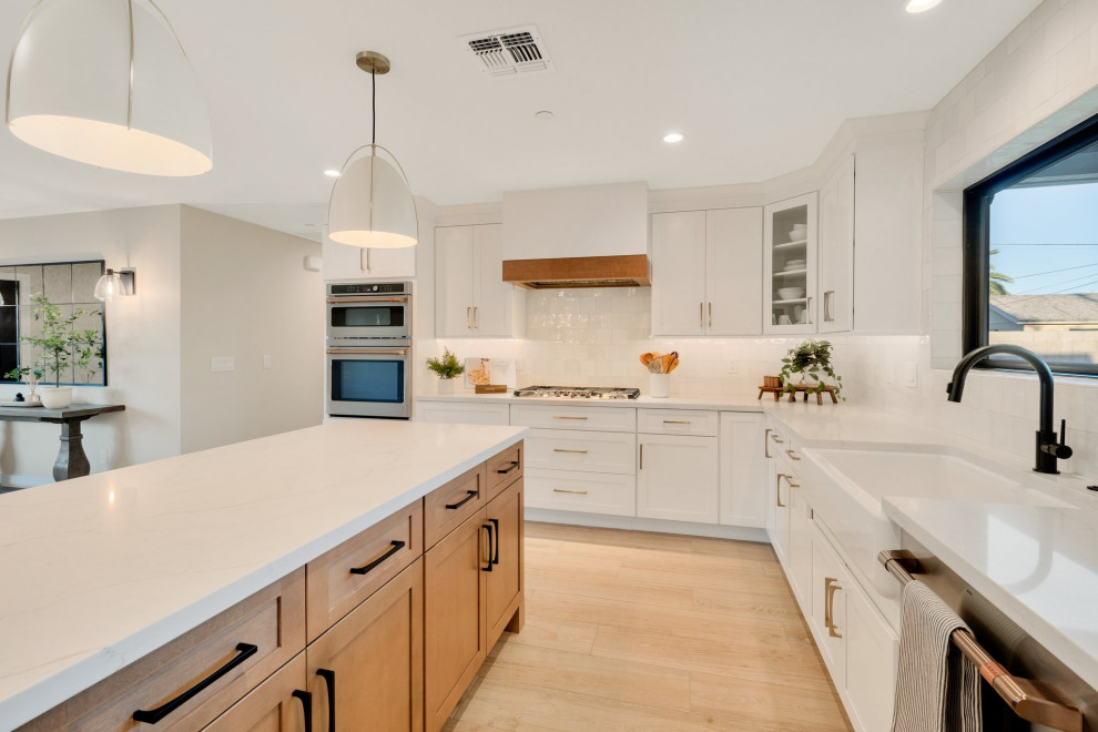 Inspiration for a large transitional l-shaped porcelain tile and beige floor kitchen pantry remodel in Phoenix with a farmhouse sink, shaker cabinets, white cabinets, quartz countertops, white backsplash, ceramic backsplash, stainless steel appliances, an island and white countertops