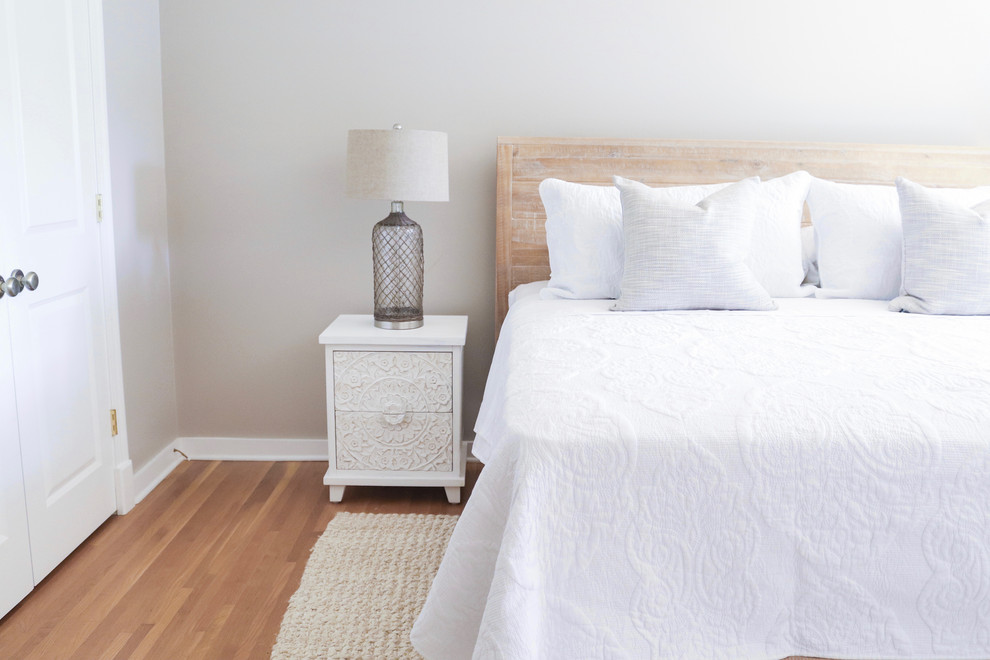 Mid-sized transitional guest bedroom with beige walls and medium hardwood floors.