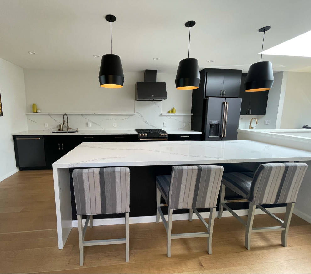 Foto di un cucina con isola centrale design di medie dimensioni con lavello sottopiano, ante lisce, ante nere, top in quarzite, elettrodomestici neri e parquet chiaro