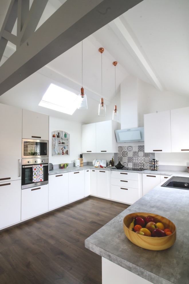 Photo of a large contemporary u-shaped kitchen in West Midlands with a drop-in sink, flat-panel cabinets, white cabinets, grey splashback, panelled appliances, no island, brown floor and grey benchtop.
