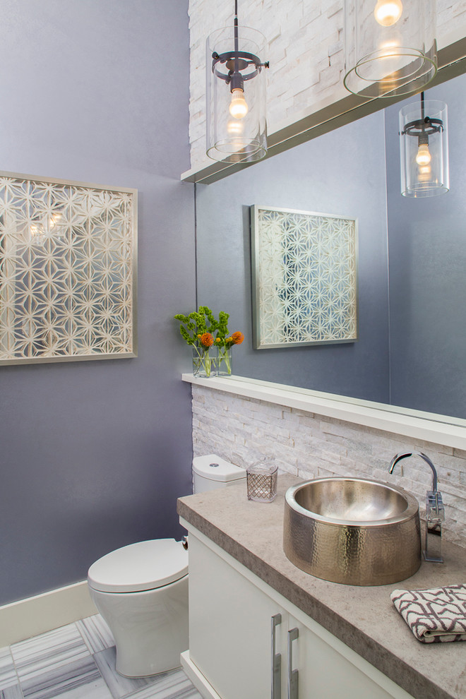 Inspiration for a large contemporary powder room in Austin with flat-panel cabinets, white cabinets, limestone benchtops, white tile, a one-piece toilet, a vessel sink, purple walls, marble floors, limestone and beige benchtops.