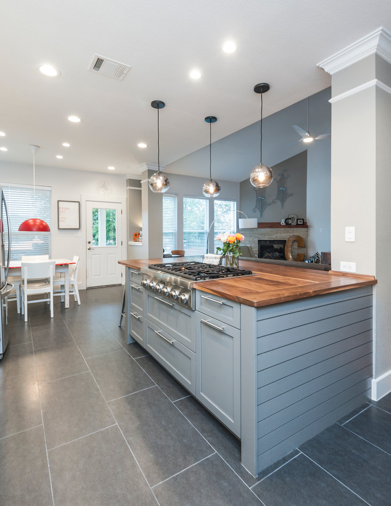 Inspiration for a large transitional l-shaped open plan kitchen in Austin with a farmhouse sink, shaker cabinets, white cabinets, wood benchtops, white splashback, ceramic splashback, stainless steel appliances, ceramic floors and with island.