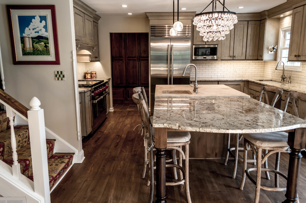This is an example of a mid-sized traditional u-shaped kitchen in Cleveland with a single-bowl sink, recessed-panel cabinets, distressed cabinets, limestone benchtops, white splashback, subway tile splashback, stainless steel appliances, porcelain floors and with island.