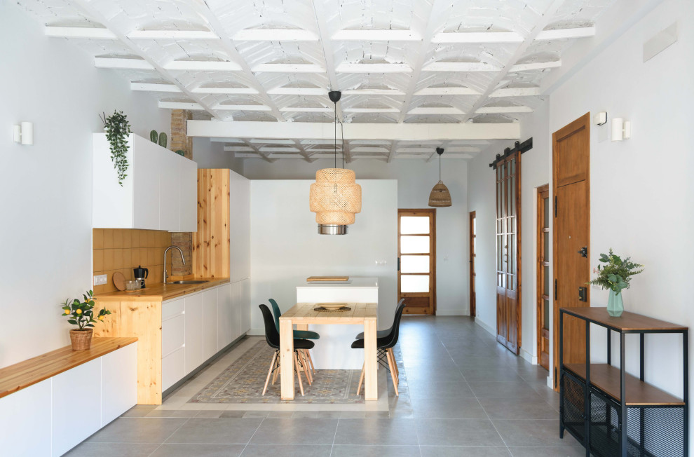 Modelo de comedor abovedado mediterráneo grande abierto con paredes blancas, suelo de baldosas de cerámica, suelo gris y alfombra