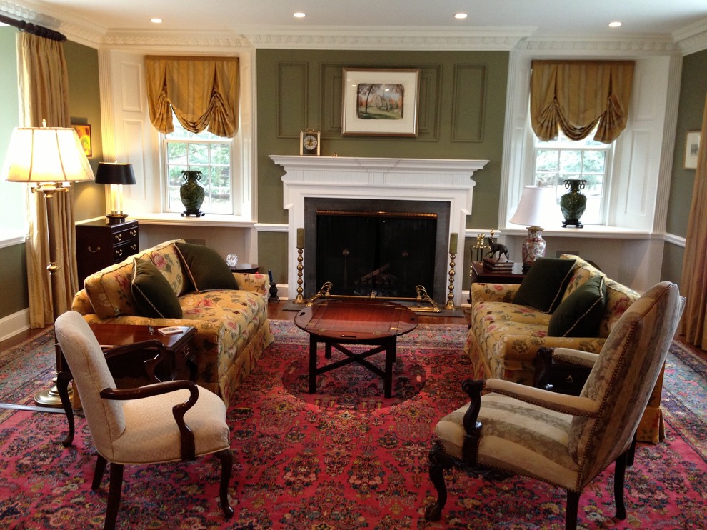Photo of a large traditional living room in Baltimore with green walls, medium hardwood floors, a standard fireplace, a wood fireplace surround and no tv.