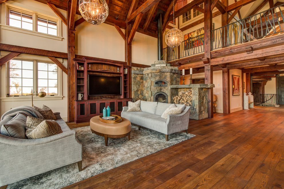 This is an example of a large country open concept living room in Other with white walls, medium hardwood floors, a corner fireplace, a stone fireplace surround and a built-in media wall.
