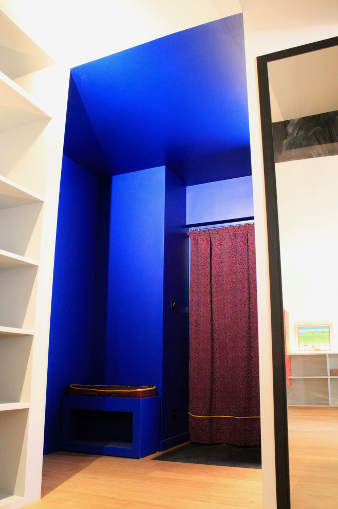 Bild på en liten funkis farstu, med blå väggar, bambugolv, en enkeldörr och en blå dörr