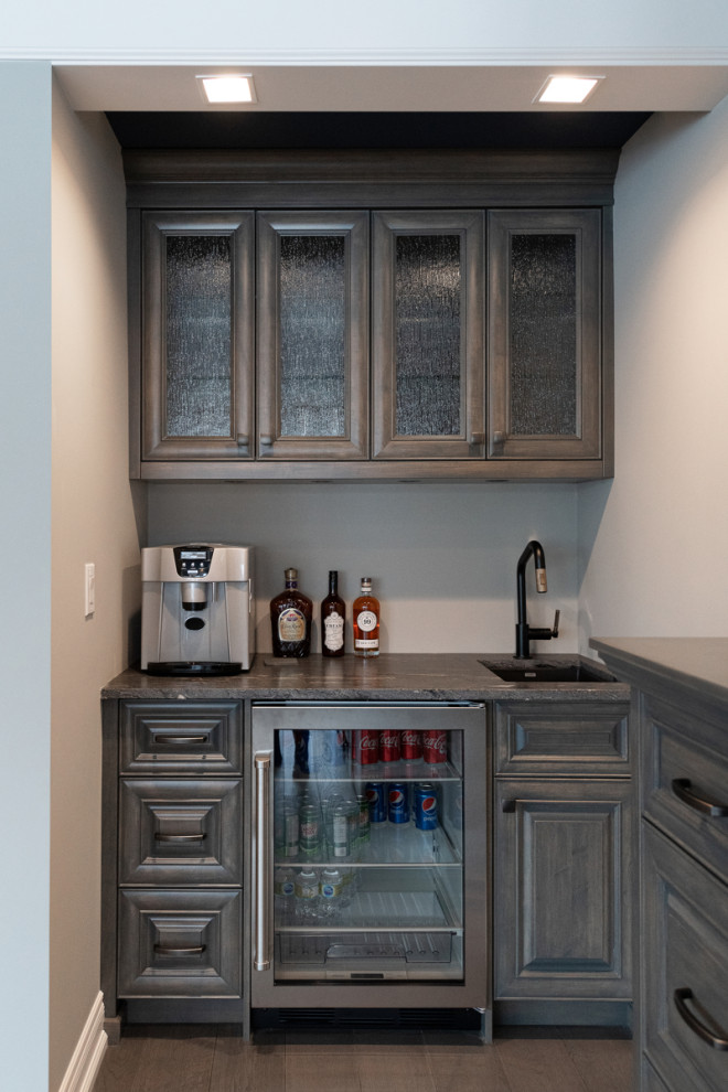 Transitional single-wall wet bar in Edmonton with an undermount sink, raised-panel cabinets, light wood cabinets, granite benchtops, light hardwood floors, brown floor and grey benchtop.