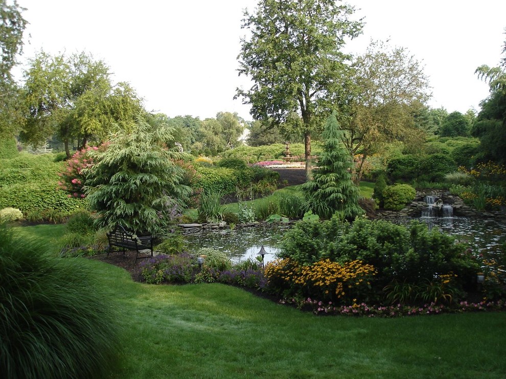 This is an example of a mid-sized traditional backyard partial sun formal garden in Other with with pond.