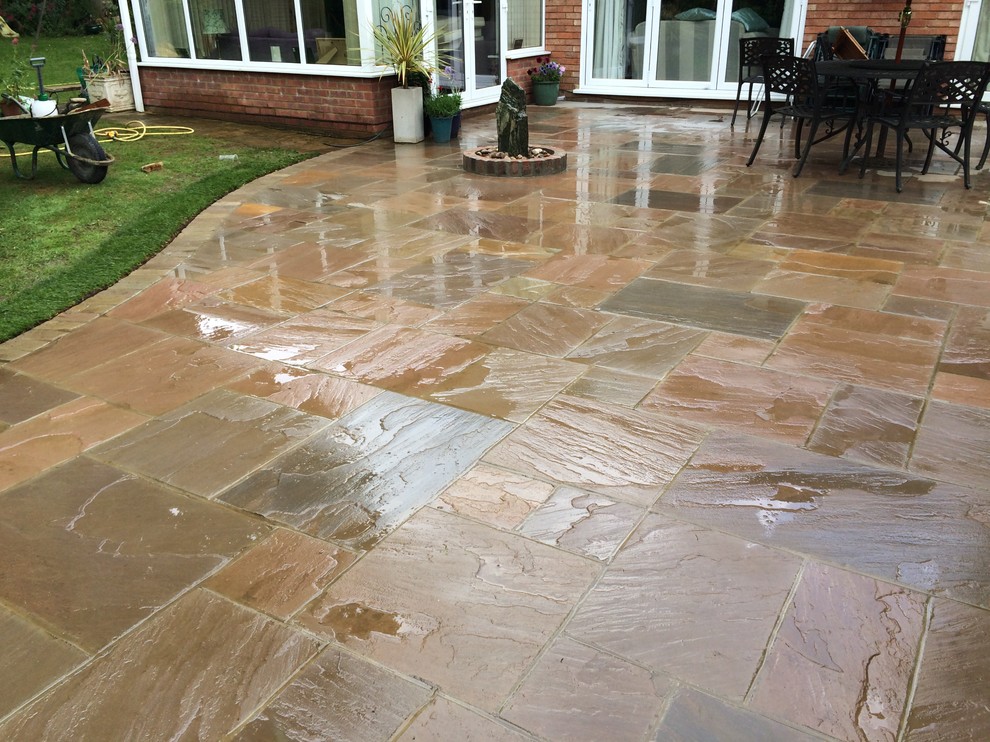 Large traditional backyard patio in Cambridgeshire with a water feature, natural stone pavers and no cover.