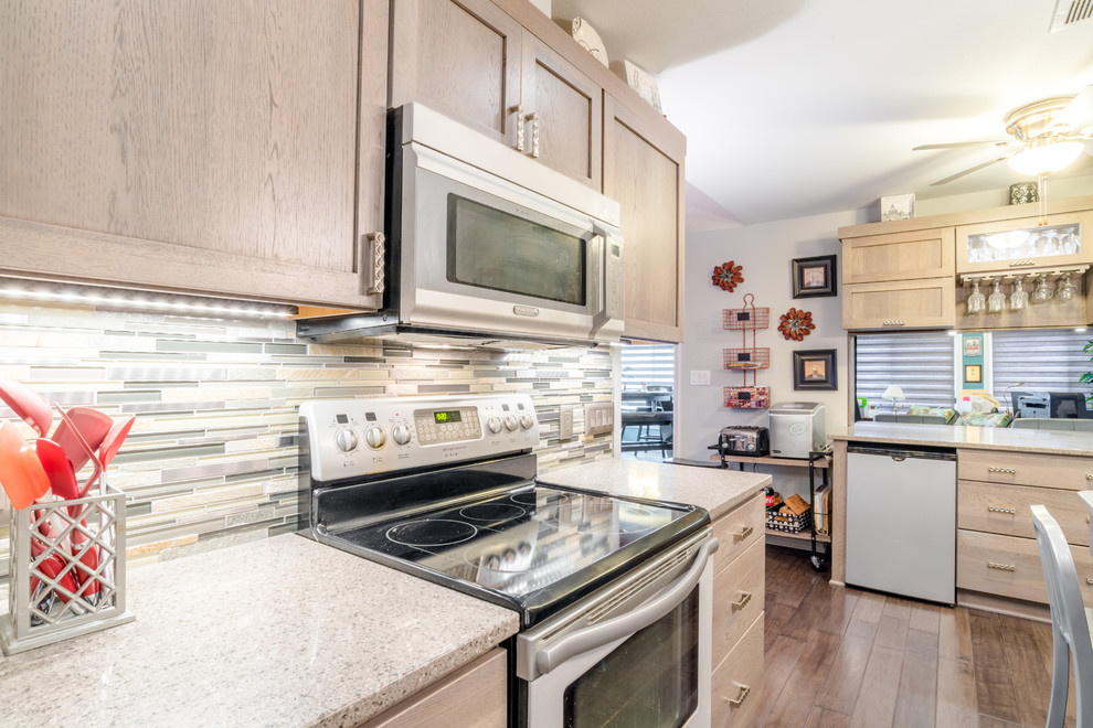 Inspiration for a mid-sized transitional u-shaped medium tone wood floor enclosed kitchen remodel in Miami with a farmhouse sink, shaker cabinets, gray cabinets, quartz countertops, gray backsplash, glass tile backsplash, white appliances and an island