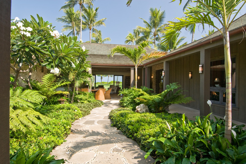 This is an example of a tropical backyard shaded garden in Hawaii with natural stone pavers.