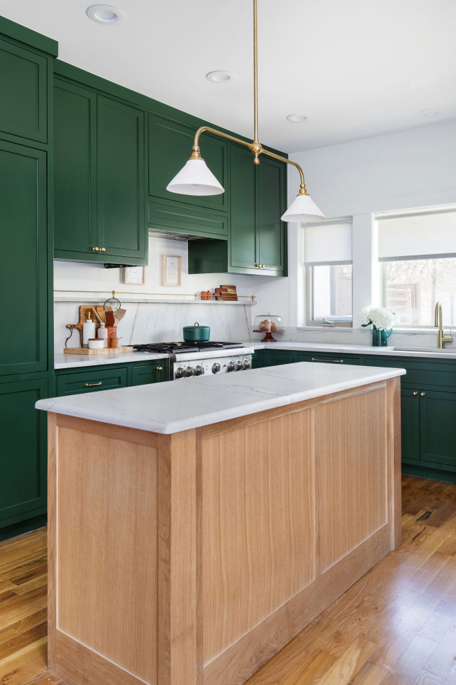 Open concept kitchen - mid-sized transitional u-shaped medium tone wood floor and brown floor open concept kitchen idea in Austin with an undermount sink, shaker cabinets, green cabinets, quartzite countertops, white backsplash, stone slab backsplash, stainless steel appliances, an island and white countertops