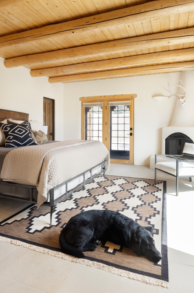 This is an example of a large master bedroom in Albuquerque with porcelain floors, a wood stove, a plaster fireplace surround, beige floor and wood.