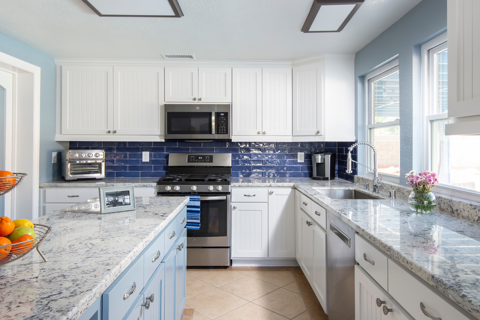 Design ideas for a mid-sized transitional galley separate kitchen in Los Angeles with a single-bowl sink, beaded inset cabinets, white cabinets, granite benchtops, blue splashback, ceramic splashback, stainless steel appliances, ceramic floors, with island, beige floor and blue benchtop.