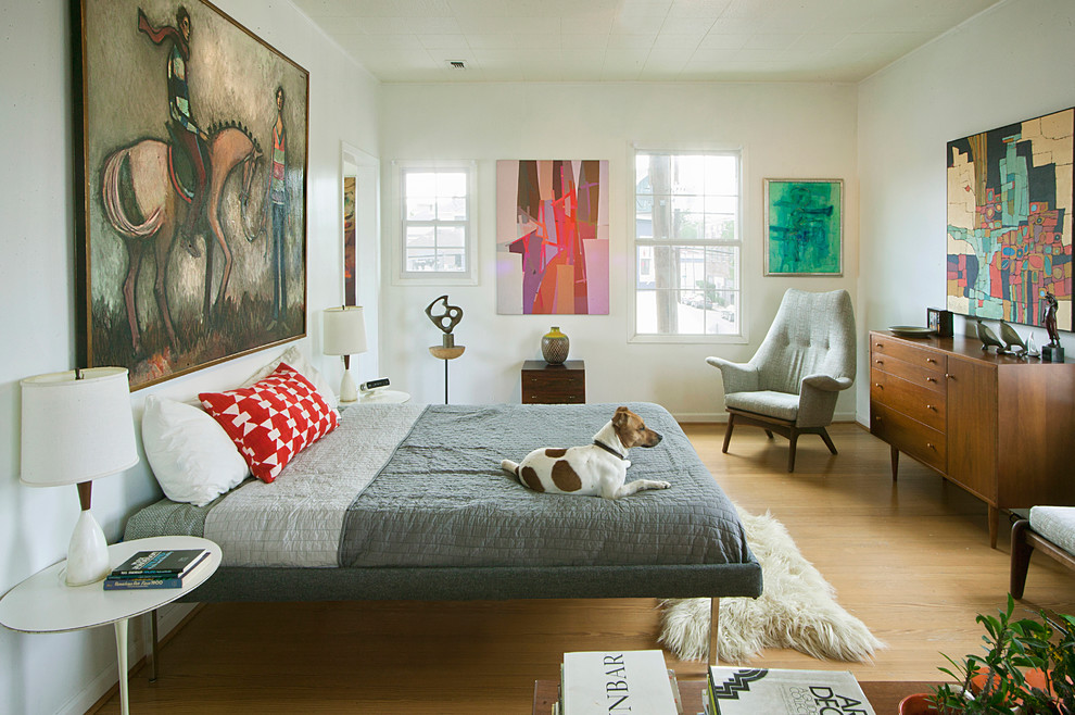 This is an example of a midcentury bedroom in Houston with white walls, light hardwood floors and no fireplace.
