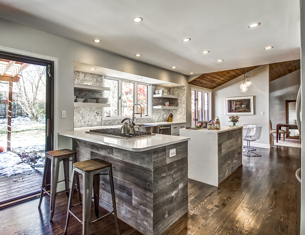 Transitional dark wood floor kitchen photo in Denver with a farmhouse sink, shaker cabinets, white cabinets, quartz countertops, stone tile backsplash and an island