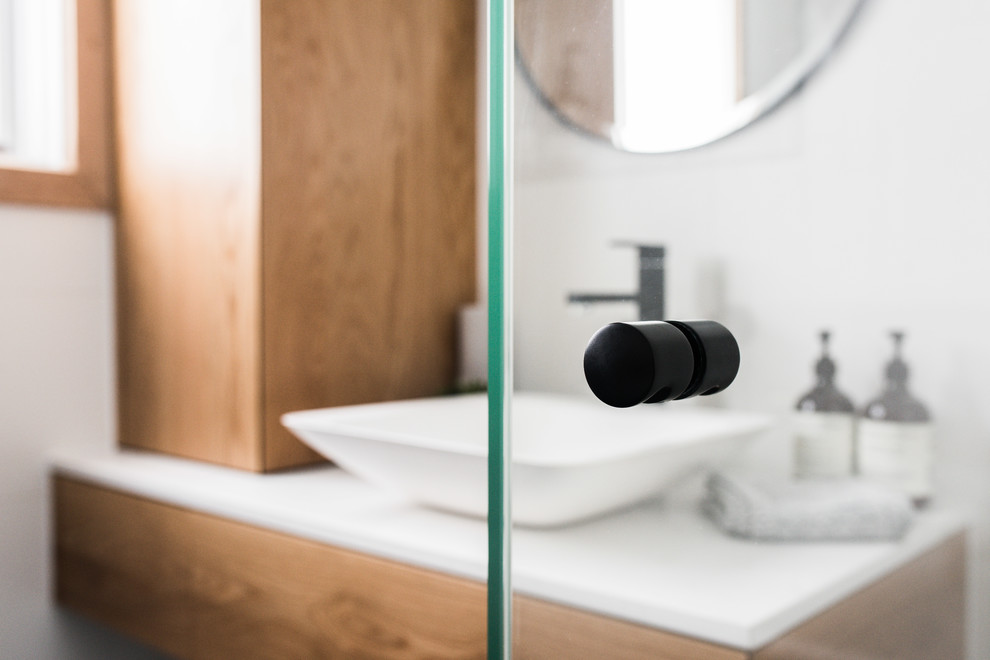Photo of a mid-sized contemporary 3/4 bathroom in Melbourne with flat-panel cabinets, medium wood cabinets, a drop-in tub, a corner shower, white tile, ceramic tile, white walls, porcelain floors, a vessel sink, engineered quartz benchtops, black floor and a hinged shower door.