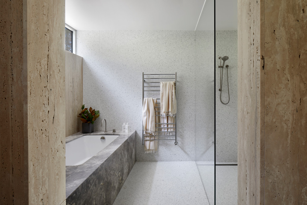 Large contemporary bathroom in Melbourne with flat-panel cabinets, brown cabinets, a drop-in tub, an open shower, a one-piece toilet, beige tile, travertine, beige walls, terrazzo floors, an undermount sink, limestone benchtops, multi-coloured floor, an open shower and grey benchtops.