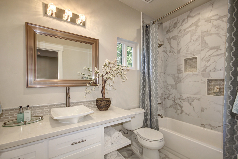 This is an example of a mid-sized traditional 3/4 bathroom in Sacramento with white cabinets, a shower/bathtub combo, a one-piece toilet, gray tile, ceramic tile, beige walls, ceramic floors, quartzite benchtops, grey floor, white benchtops, a single vanity and a built-in vanity.