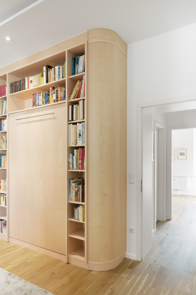 Diseño de sala de estar con biblioteca cerrada clásica de tamaño medio sin televisor con paredes verdes, suelo de madera clara, bandeja y madera