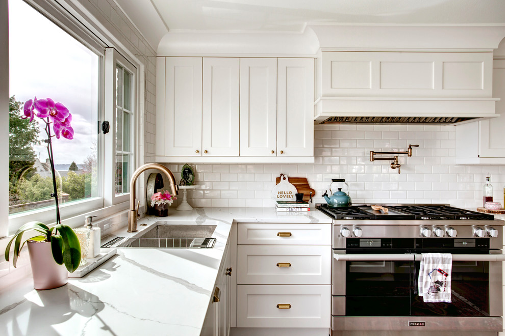 Transitional l-shaped open plan kitchen in Seattle with an undermount sink, shaker cabinets, white cabinets, marble benchtops, white splashback, subway tile splashback, stainless steel appliances and no island.