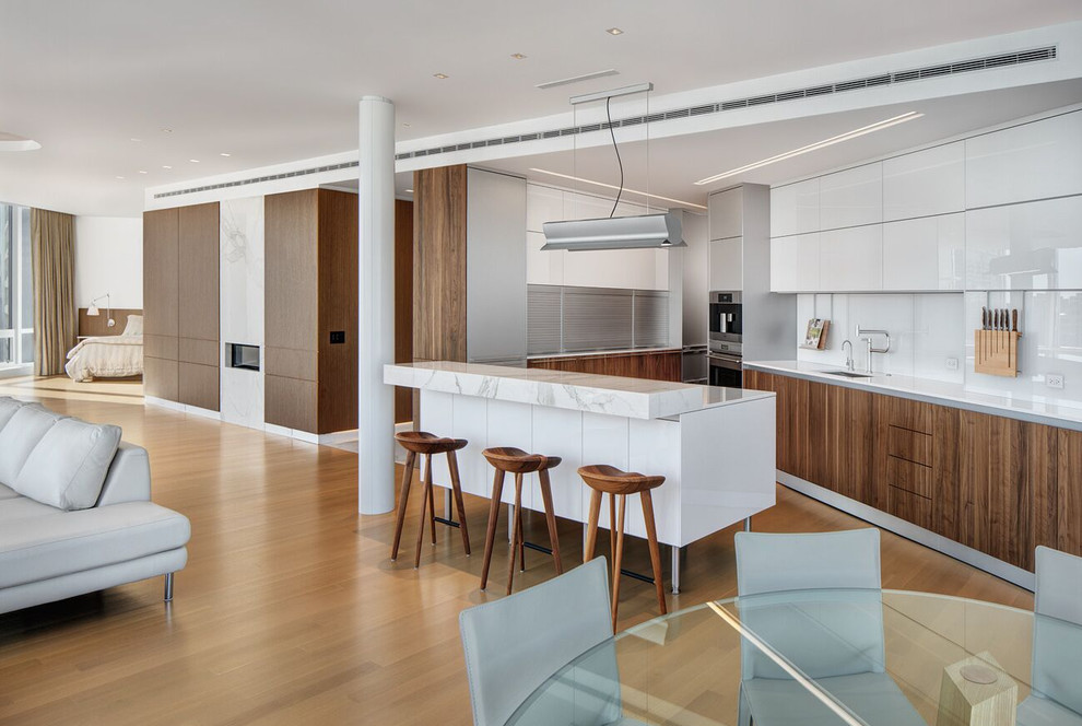 Design ideas for a contemporary u-shaped open plan kitchen in Chicago with an undermount sink, flat-panel cabinets, dark wood cabinets, white splashback, glass sheet splashback, stainless steel appliances, medium hardwood floors and with island.