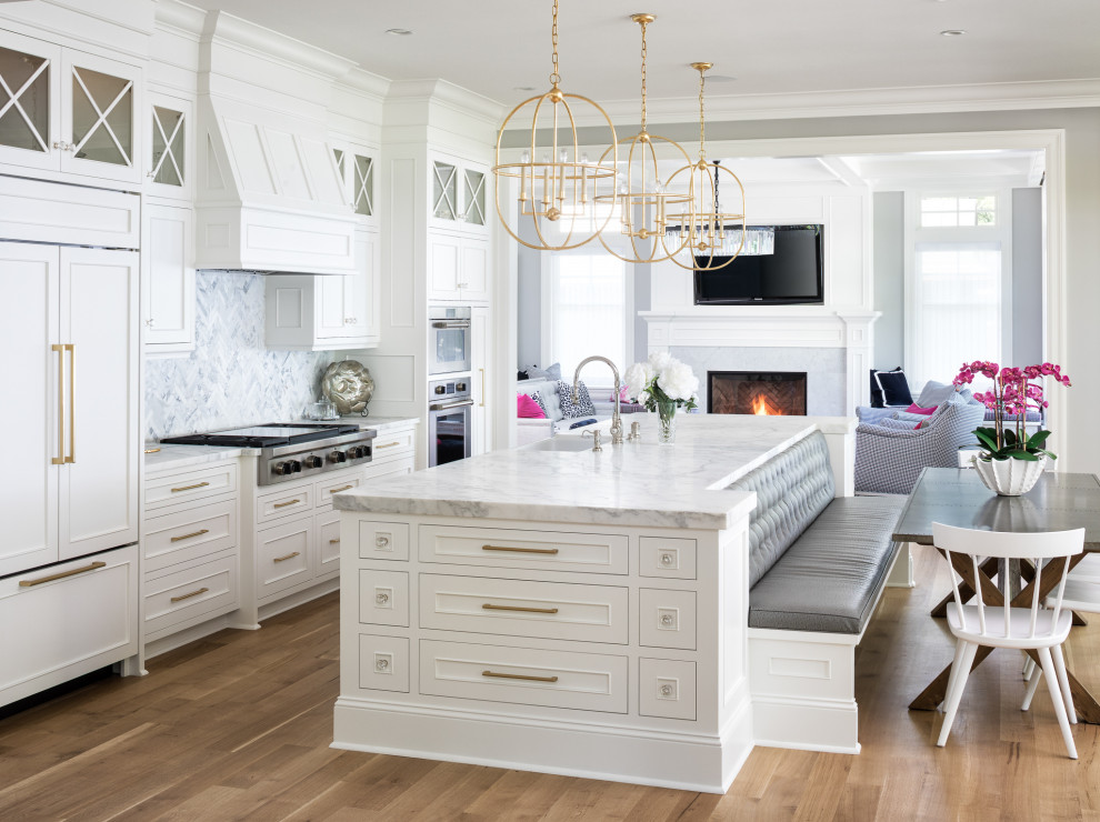 Beach style galley medium tone wood floor and brown floor kitchen photo in Minneapolis with a farmhouse sink, recessed-panel cabinets, white cabinets, gray backsplash, stainless steel appliances, an island and white countertops