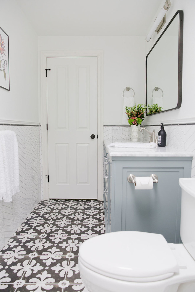 Inspiration for a mid-sized transitional 3/4 bathroom in Seattle with furniture-like cabinets, blue cabinets, an alcove tub, a shower/bathtub combo, a one-piece toilet, white tile, porcelain tile, white walls, porcelain floors, an undermount sink, marble benchtops, multi-coloured floor, a shower curtain and grey benchtops.