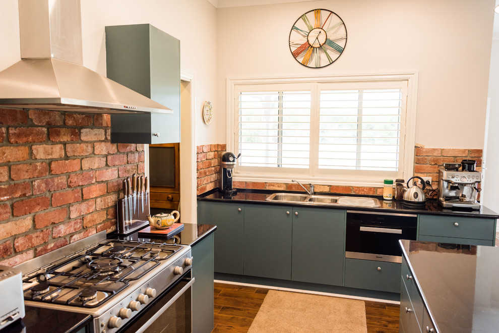 Photo of a small country galley kitchen pantry in Geelong with a double-bowl sink, green cabinets, laminate benchtops, red splashback, brick splashback, stainless steel appliances, linoleum floors, with island and brown floor.