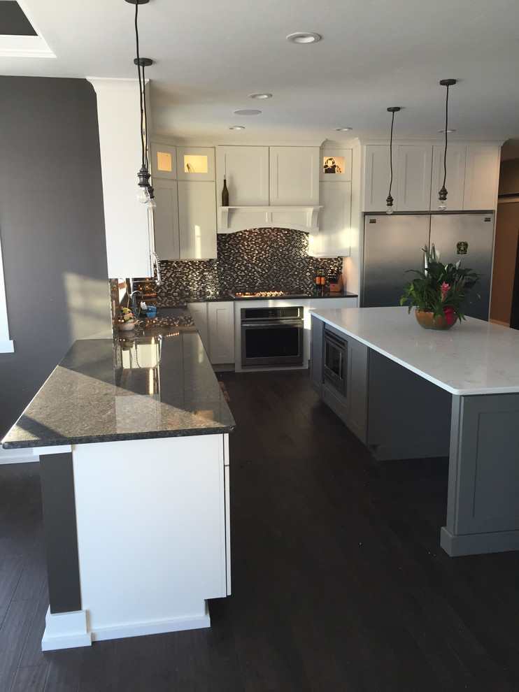 Inspiration for a mid-sized transitional l-shaped dark wood floor and black floor kitchen remodel in Minneapolis with a farmhouse sink, shaker cabinets, white cabinets, quartzite countertops, multicolored backsplash, mosaic tile backsplash, stainless steel appliances and an island