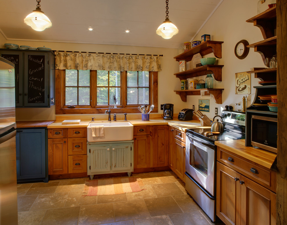 This is an example of a small country u-shaped separate kitchen in Milwaukee with a farmhouse sink, beaded inset cabinets, medium wood cabinets, wood benchtops, stainless steel appliances, travertine floors and no island.
