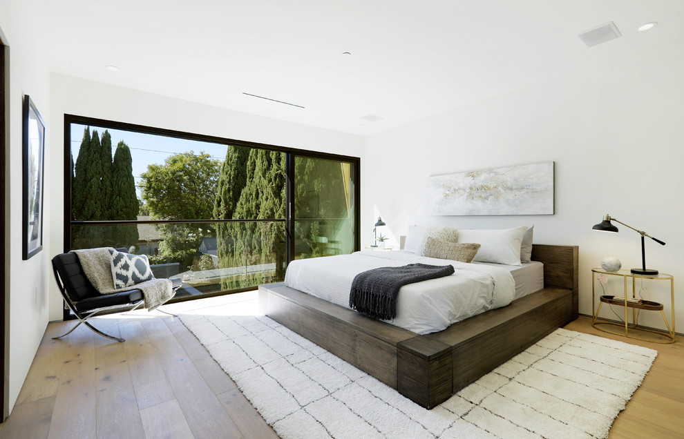 This is an example of a contemporary master bedroom in Los Angeles with white walls, light hardwood floors and beige floor.