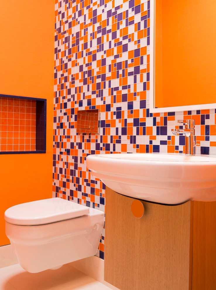 Inspiration for a small midcentury powder room in Houston with flat-panel cabinets, light wood cabinets, a wall-mount toilet, multi-coloured tile, ceramic tile, orange walls, an integrated sink and porcelain floors.