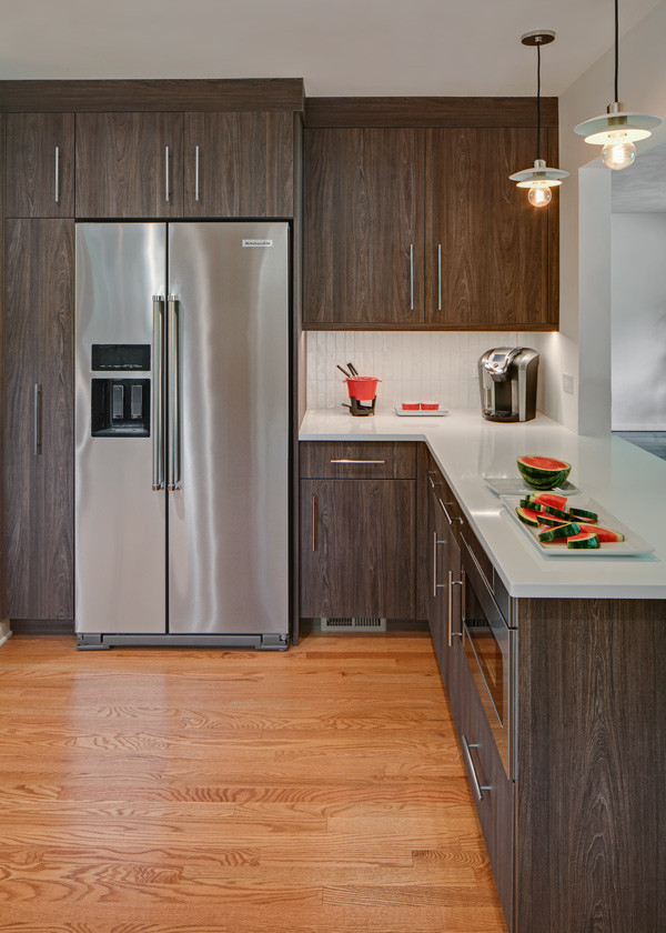 Small mid-century modern l-shaped light wood floor and brown floor kitchen pantry photo in Chicago with a farmhouse sink, flat-panel cabinets, dark wood cabinets, quartz countertops, white backsplash, ceramic backsplash, stainless steel appliances and white countertops