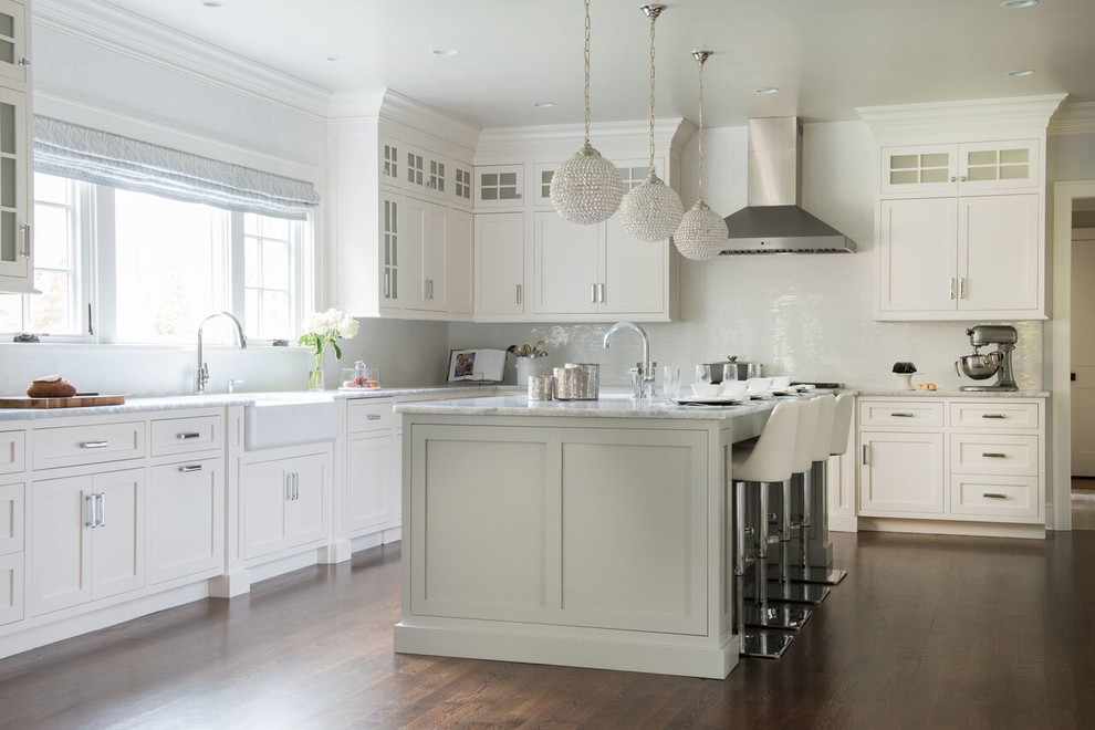 Design ideas for a mid-sized transitional l-shaped separate kitchen in DC Metro with a farmhouse sink, shaker cabinets, white cabinets, marble benchtops, white splashback, matchstick tile splashback, medium hardwood floors and with island.