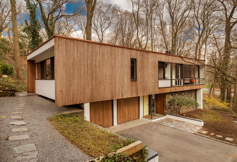 This is an example of a mid-sized midcentury two-storey beige exterior in New York with a flat roof and wood siding.