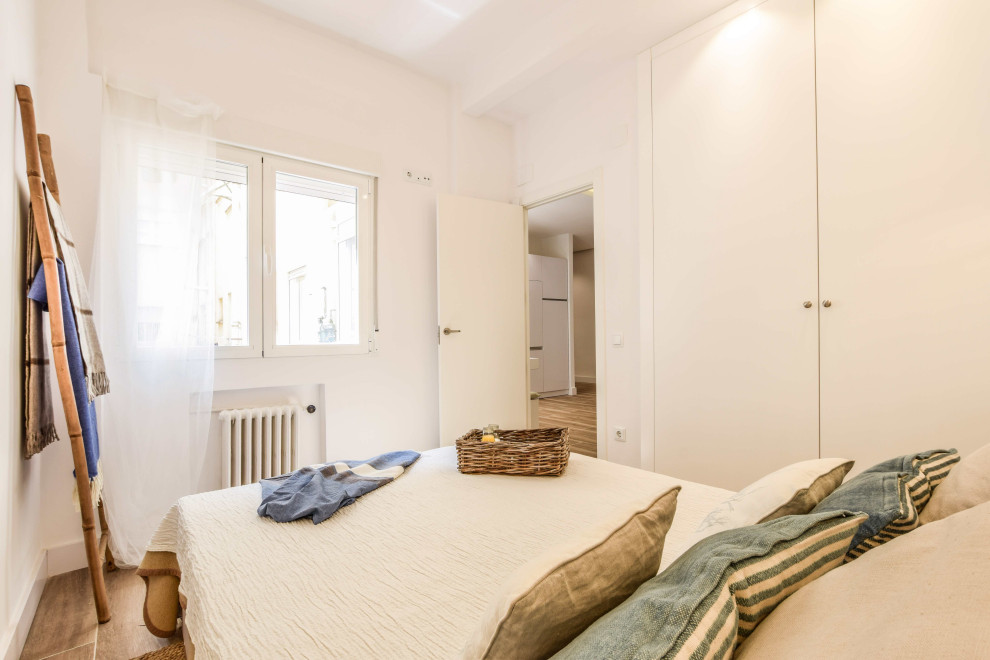 Стильный дизайн: гостевая спальня среднего размера, (комната для гостей), в белых тонах с отделкой деревом: освещение в средиземноморском стиле с белыми стенами, полом из керамогранита и коричневым полом - последний тренд