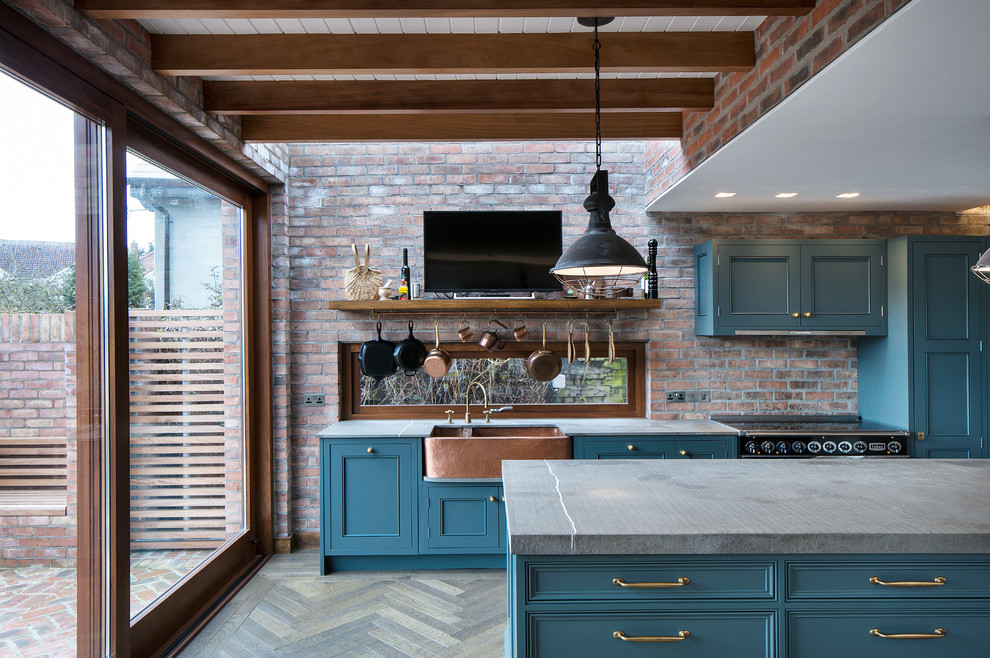 Photo of a mid-sized industrial eat-in kitchen in Dublin with a farmhouse sink, shaker cabinets, blue cabinets, quartz benchtops, black appliances, dark hardwood floors, with island and grey benchtop.