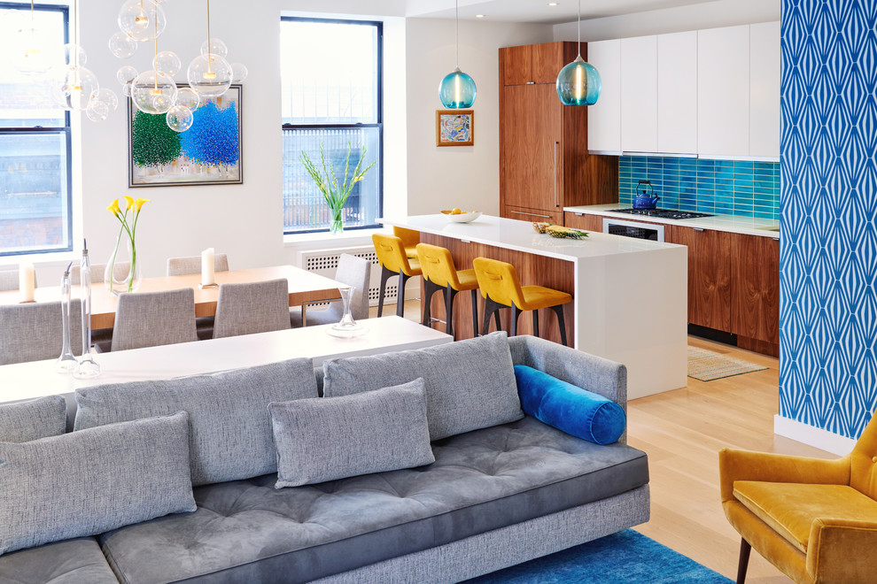 This is an example of a contemporary galley open plan kitchen in New York with flat-panel cabinets, medium wood cabinets, blue splashback, panelled appliances, light hardwood floors, with island and beige floor.