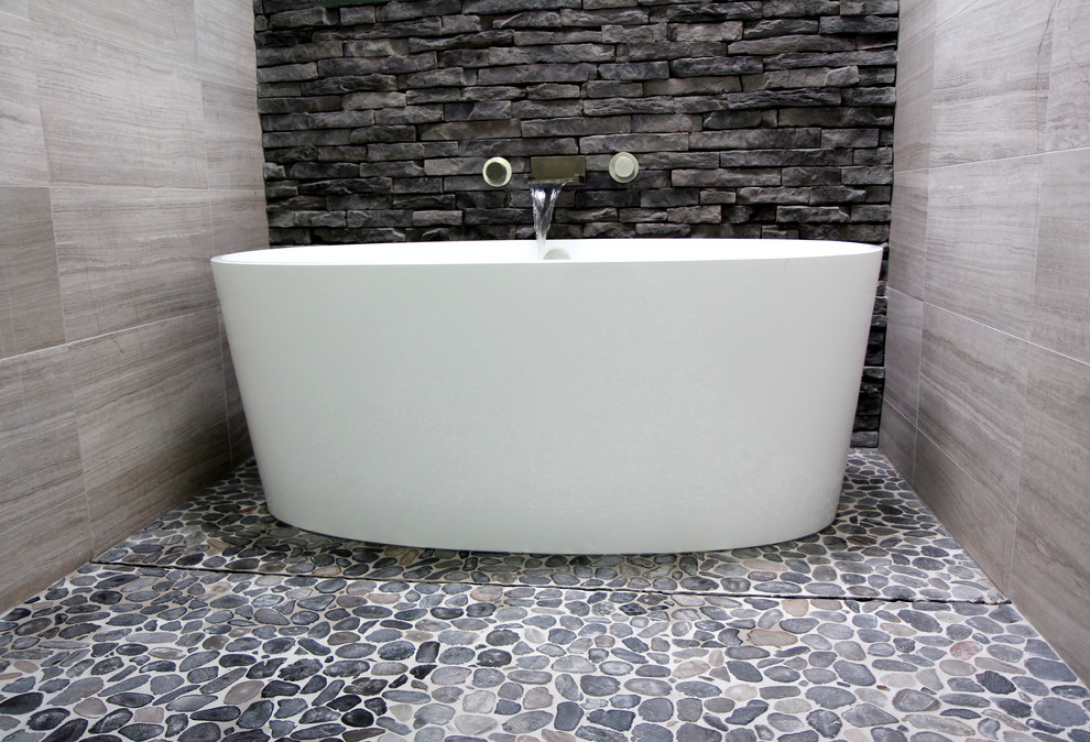 Mid-sized trendy master gray tile and stone tile limestone floor, gray floor, double-sink and vaulted ceiling bathroom photo in Atlanta with a vessel sink, gray cabinets, granite countertops, a two-piece toilet, flat-panel cabinets, white walls, black countertops, a niche and a floating vanity